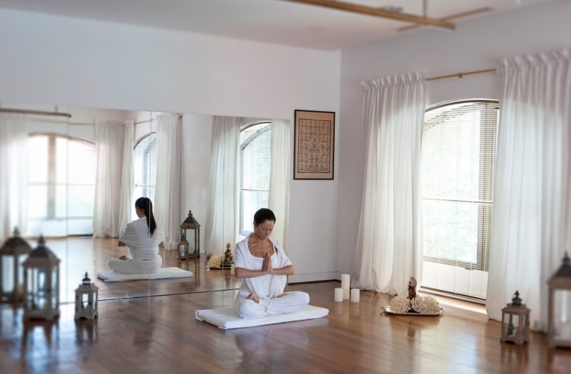 women sit on wood floor in yoga positions