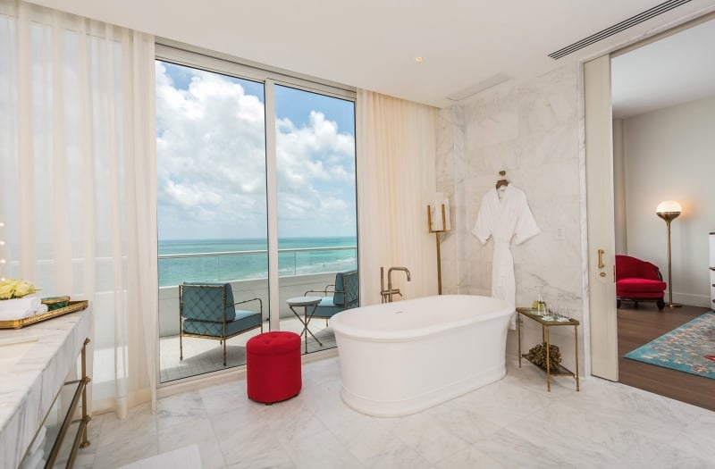 hotel bathroom with tub and balcony over the ocean