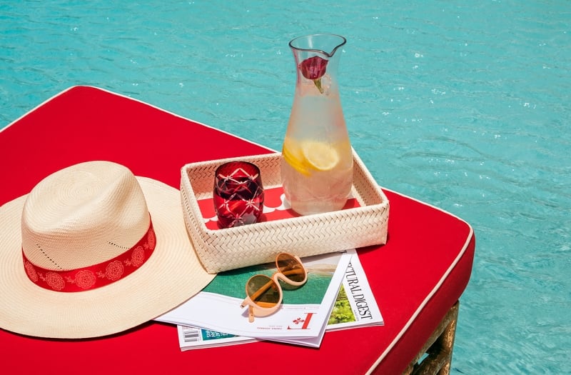 table next to pool with lemonade and a hat