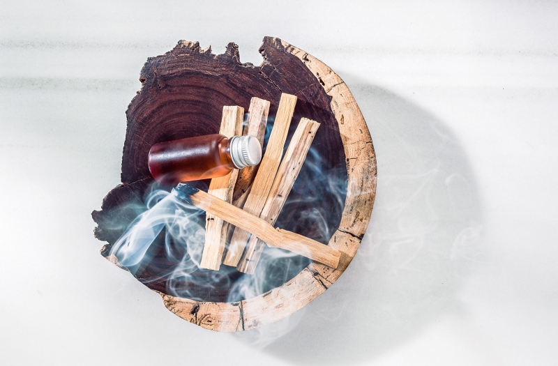 wooden bowl with wood smoking and small bottle