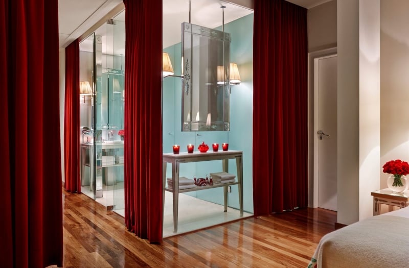 glass walled hotel suite bathroom with velvet curtains