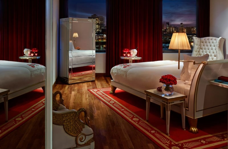 hotel bedroom with large windows overlooking city
