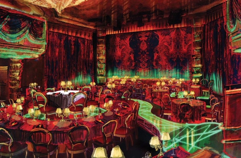 red and yellow light bathes an indoor theater seating area with green lit walking paths through the seats