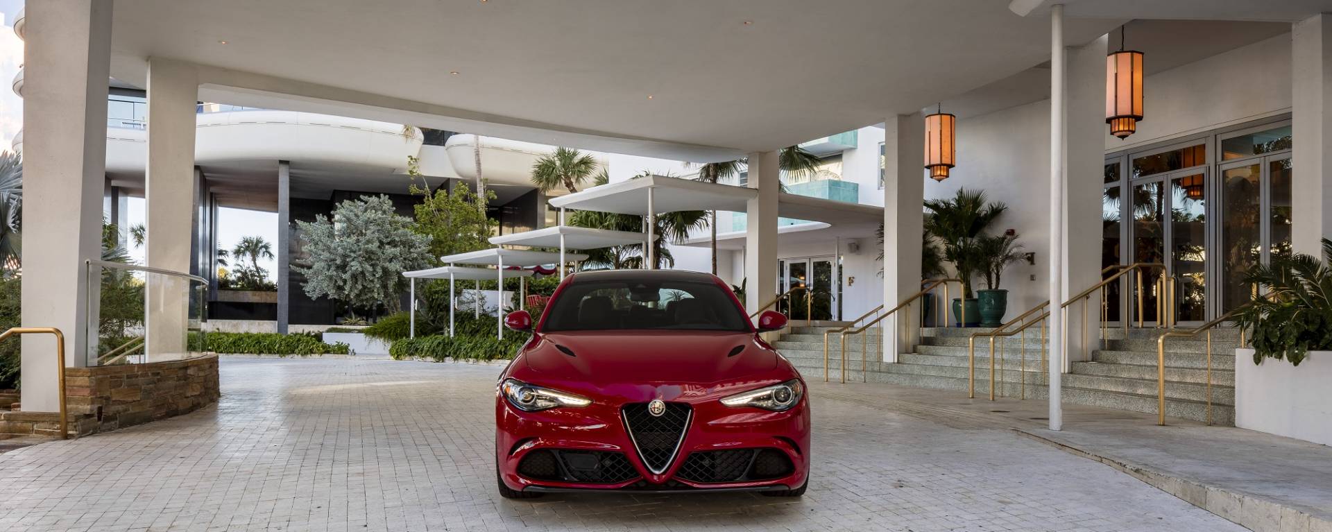 red alfa romeo car parked under Faena sign