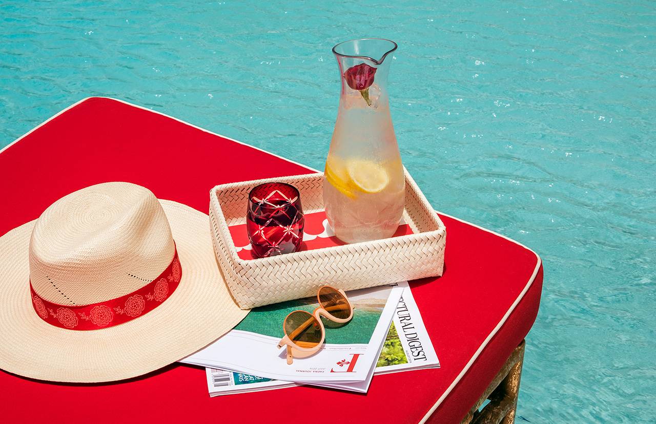 table next to pool with lemonade and a hat