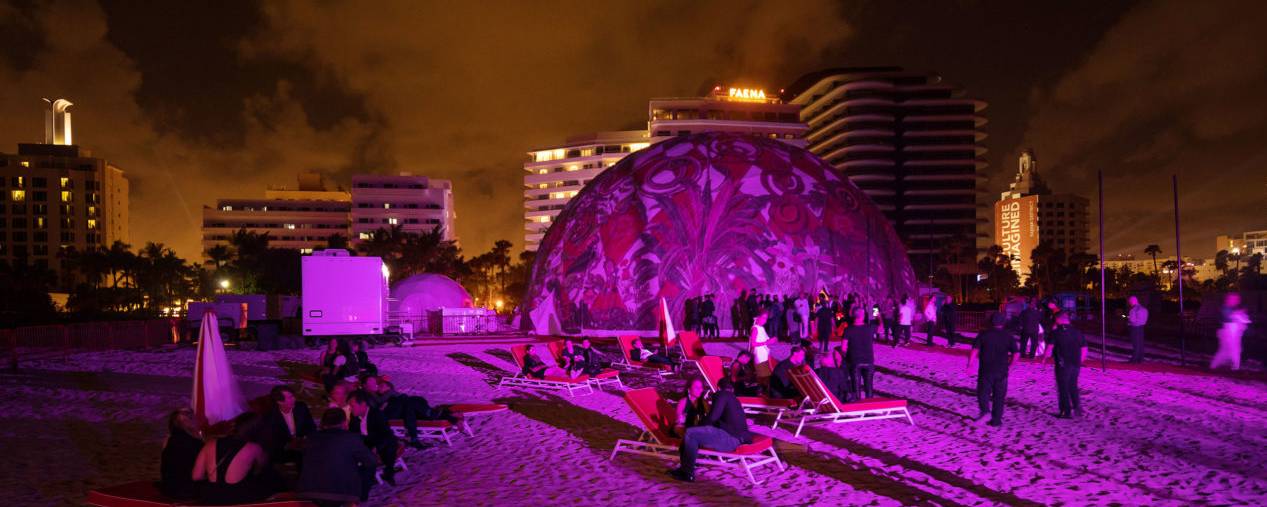 Lit up dome on beach with people socializing