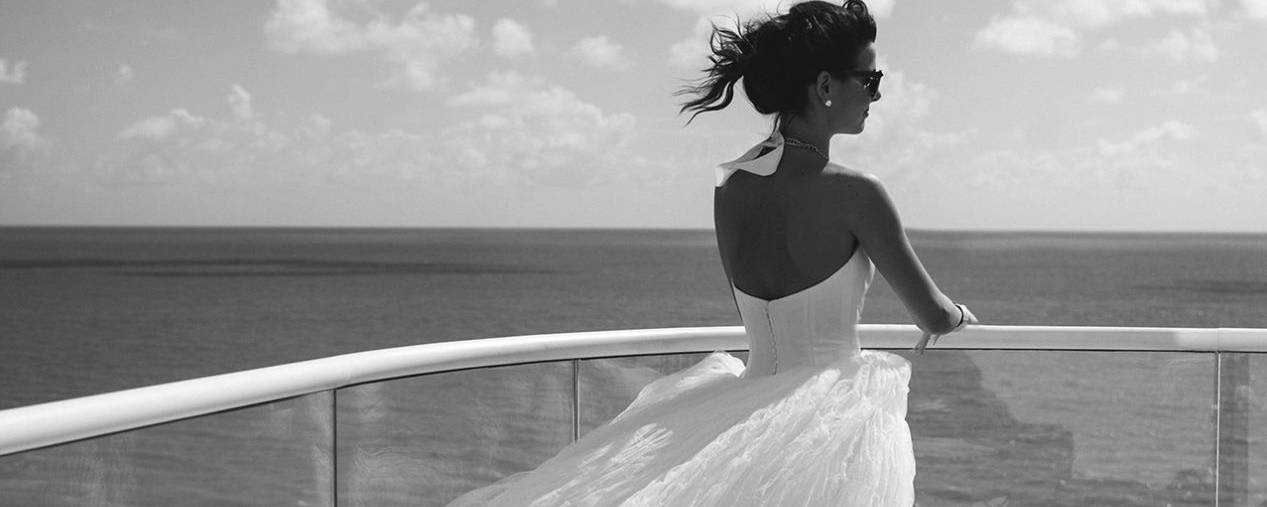Bride in wedding dress looking out over ocean