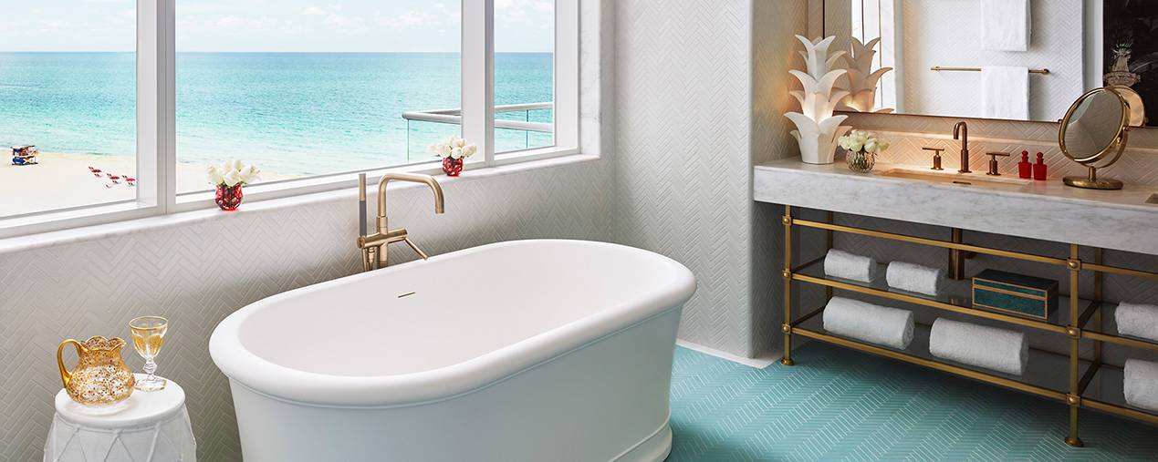 interior of bathroom with tub sitting in front of window with ocean in background
