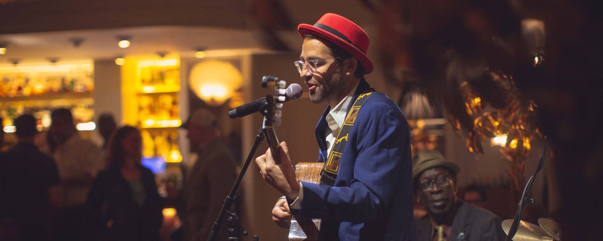 man in a red hat singing on a small stage
