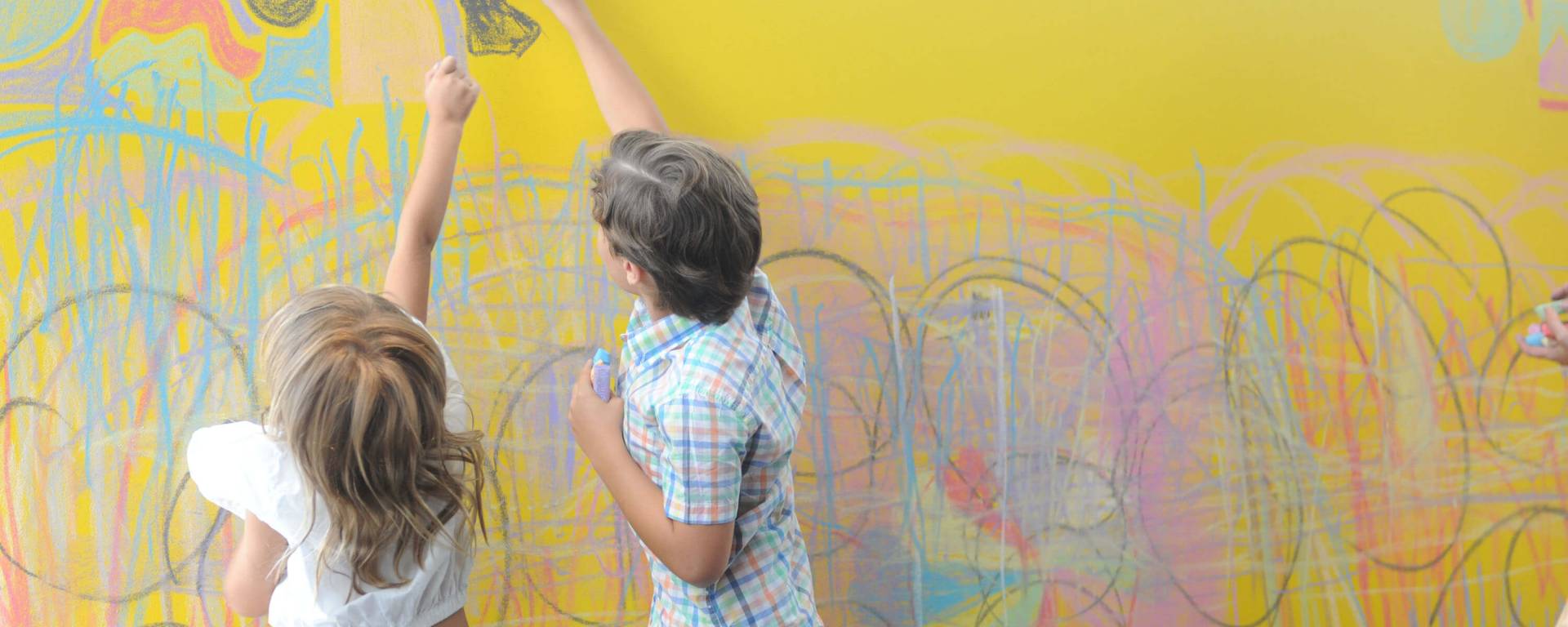 children drawing on a yellow wall
