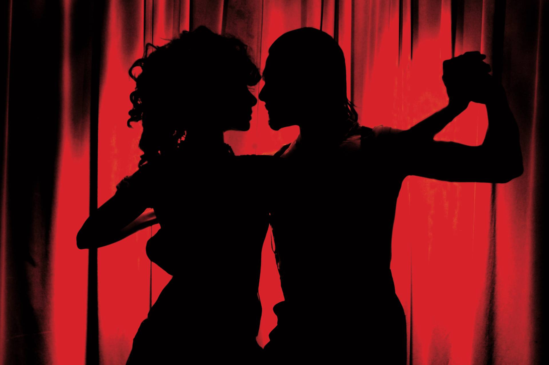 silhouette of two people dancing with red curtain backdrop