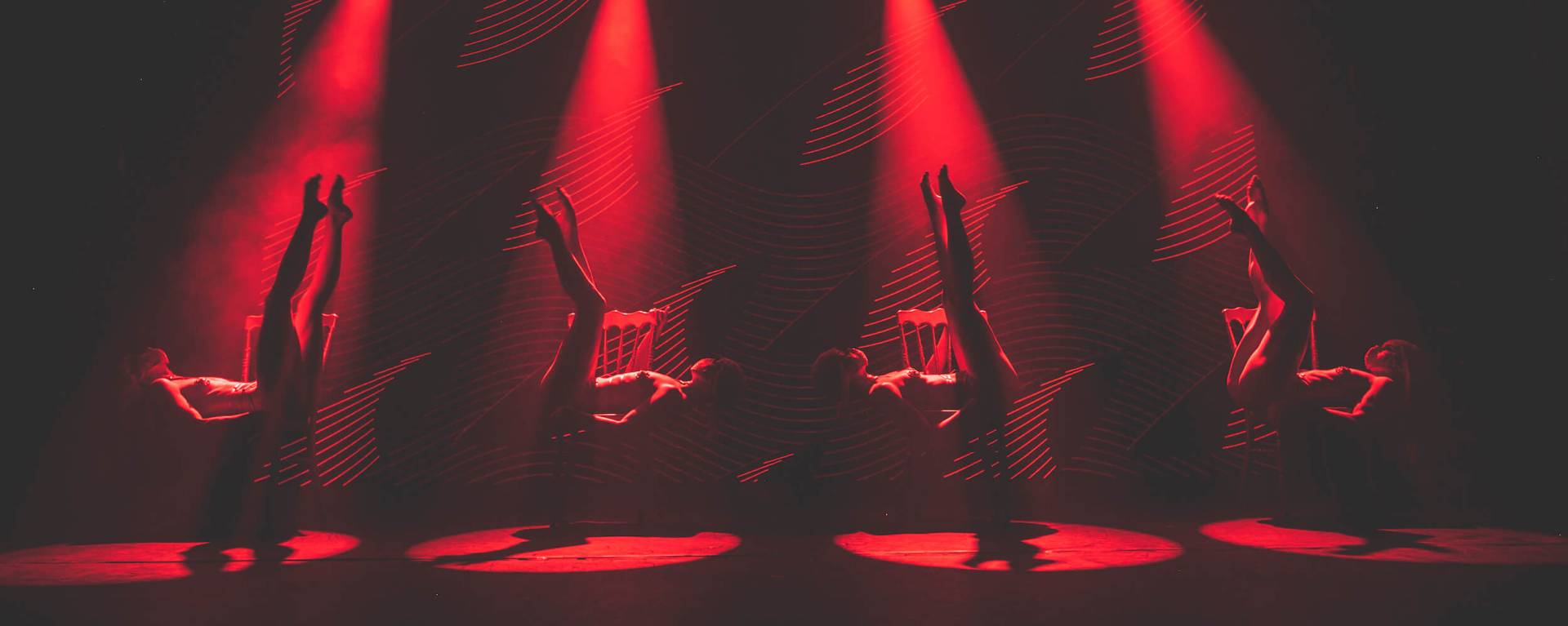 four Tryst Caberet dancers bathed in red spotlights