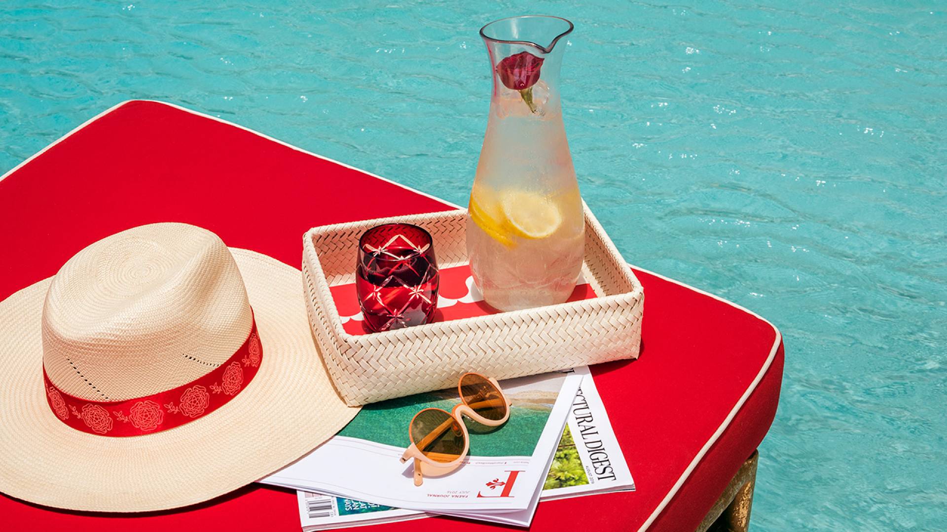 table next to pool with lemonade and a hat