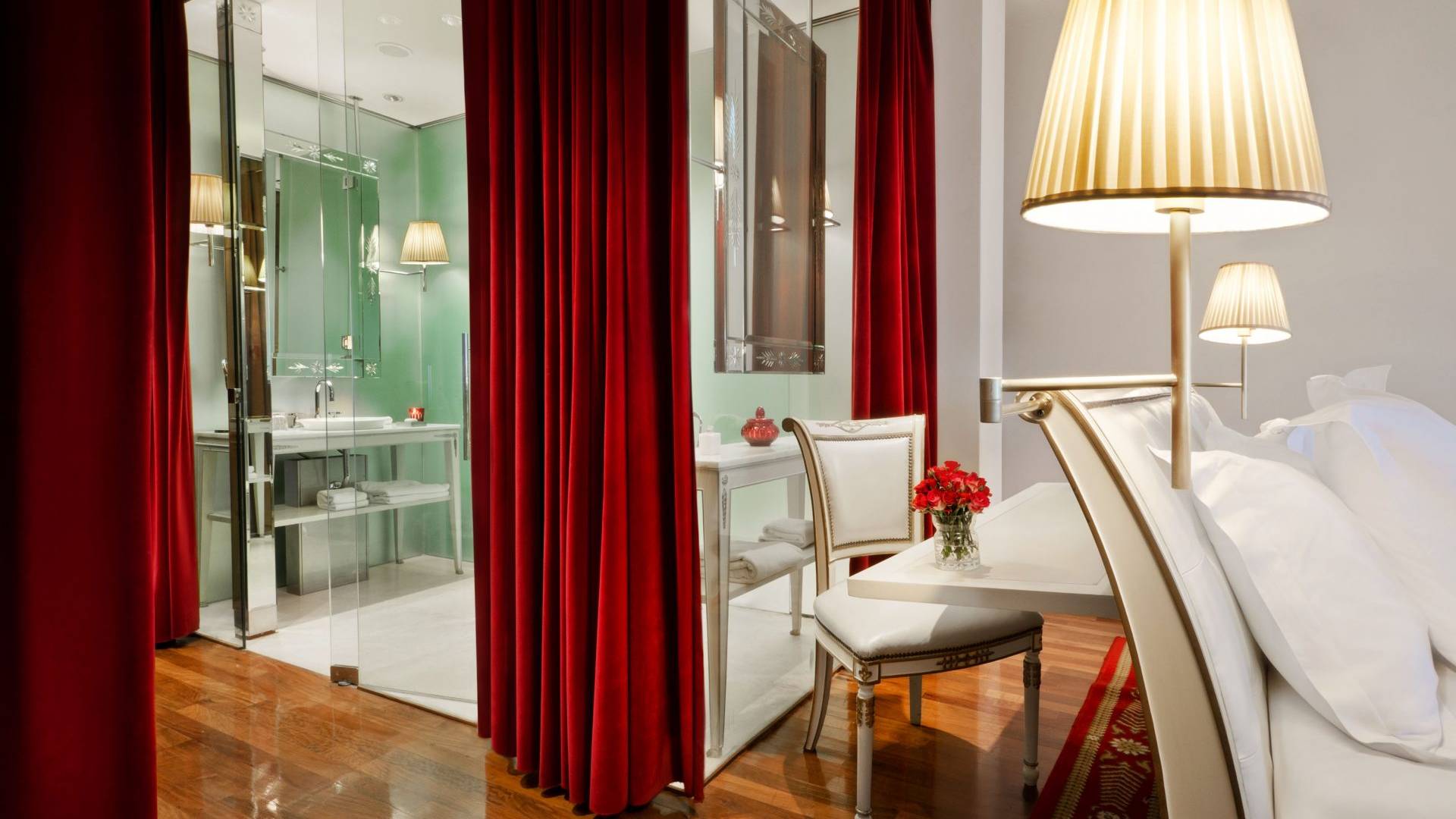glass walled hotel suite bathroom with velvet curtains