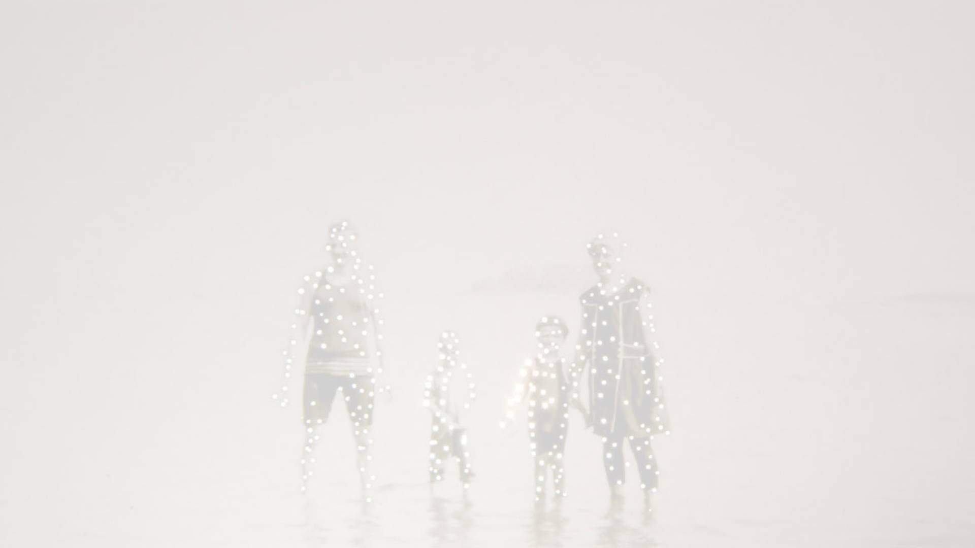 Greyed-out photograph of a family standing in the water with dots of light on their bodies.