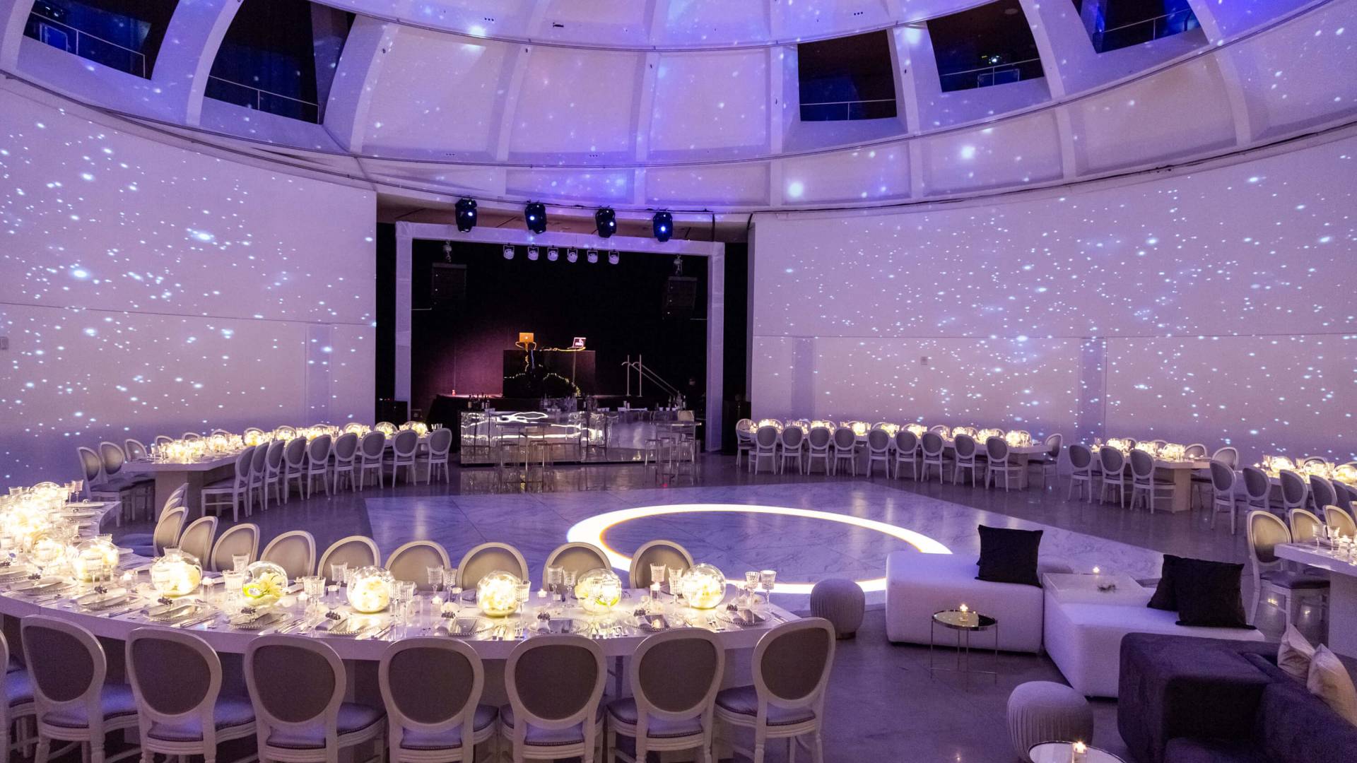 circular table for wedding reception with white flowers and purple lighting