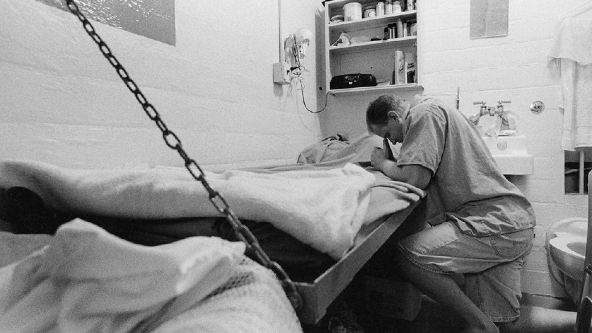 Man praying in prison cell