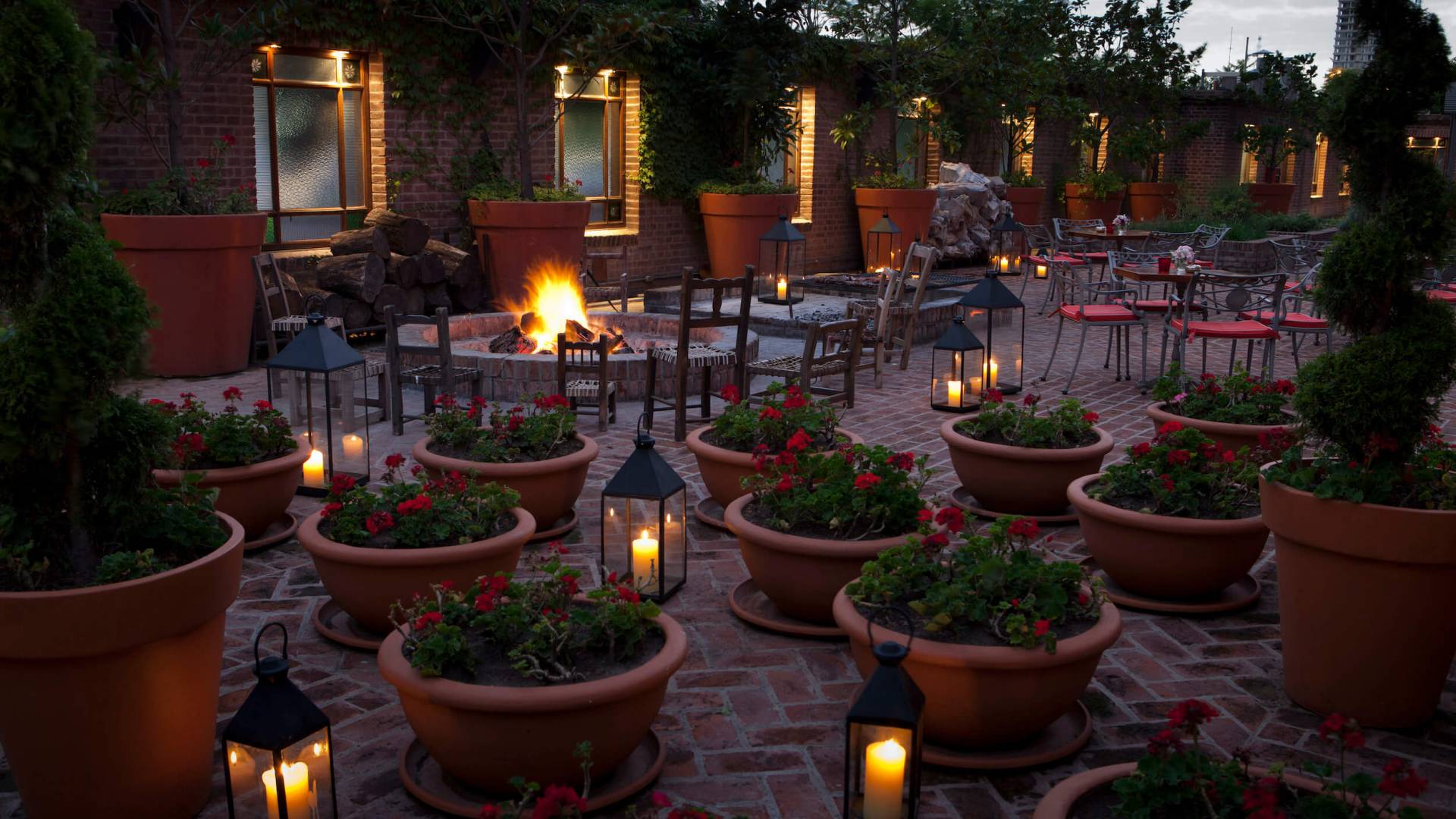 outdoor patio with multiple seating areas and shrubs in pots