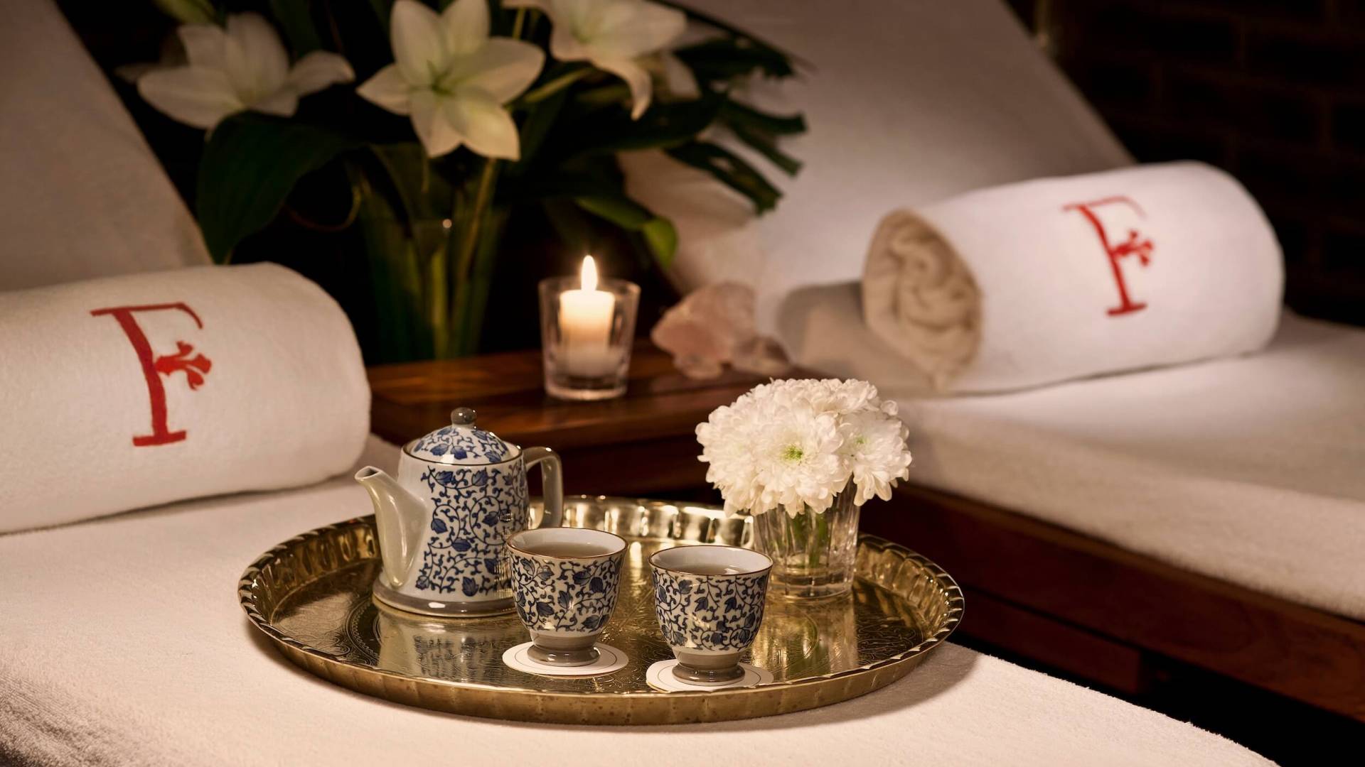 tray of tea cups and teapot sit on chaise lounges with F embossed towels 