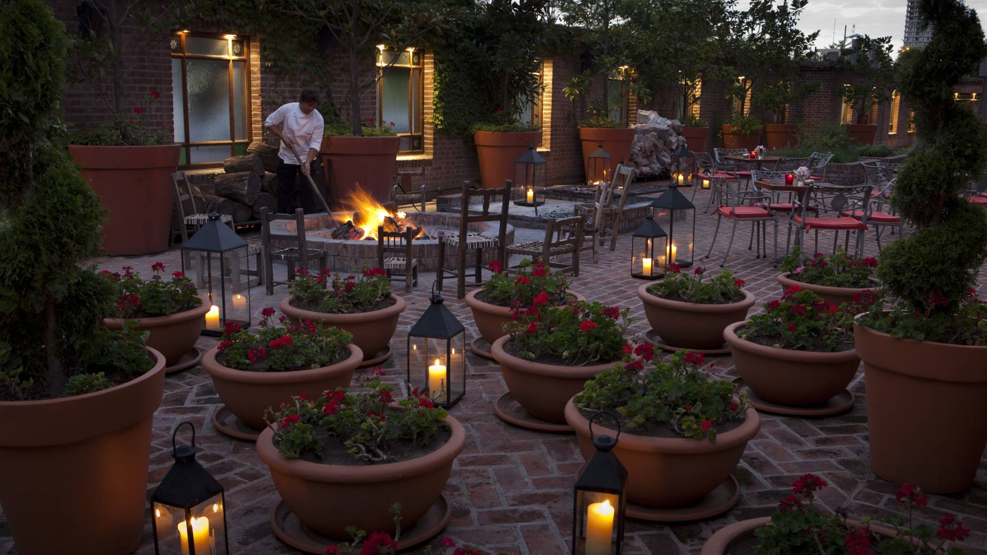 outdoor patio with multiple seating areas and shrubs in pots