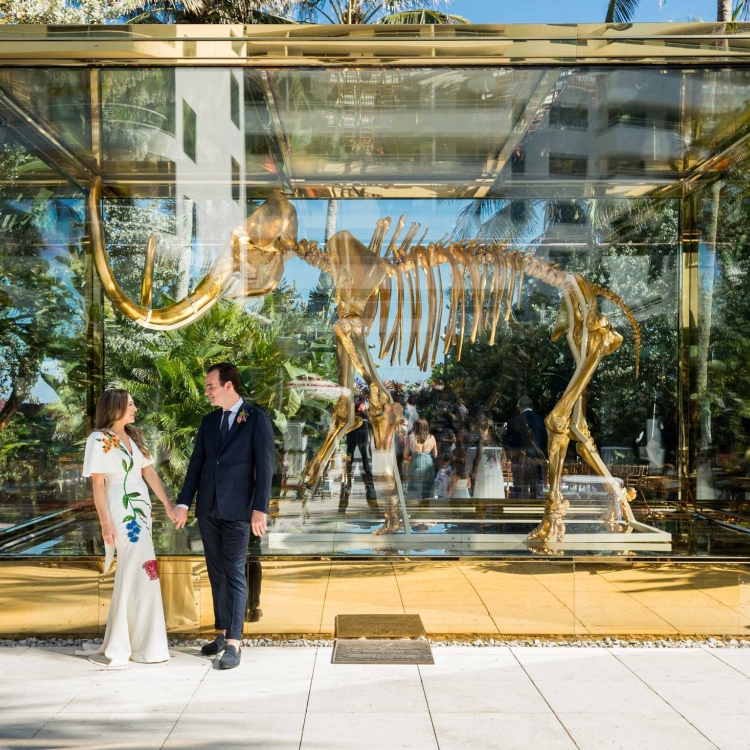 Husband and wife looking at eachother while in front of a large mammoth statue