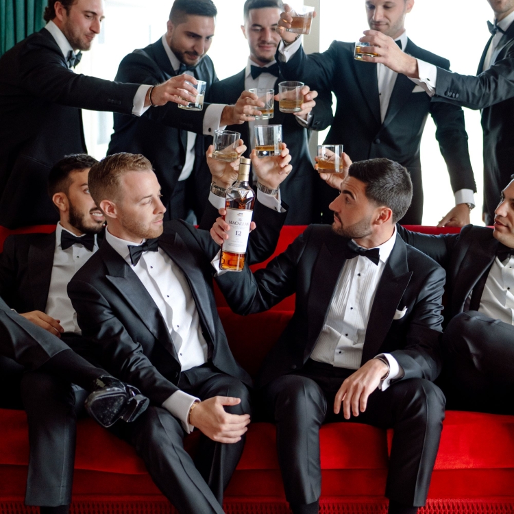 grooms mean sitting on a red couch sharing a toast
