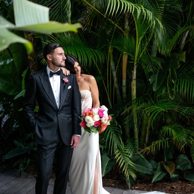 Bride and groom in front of large plants