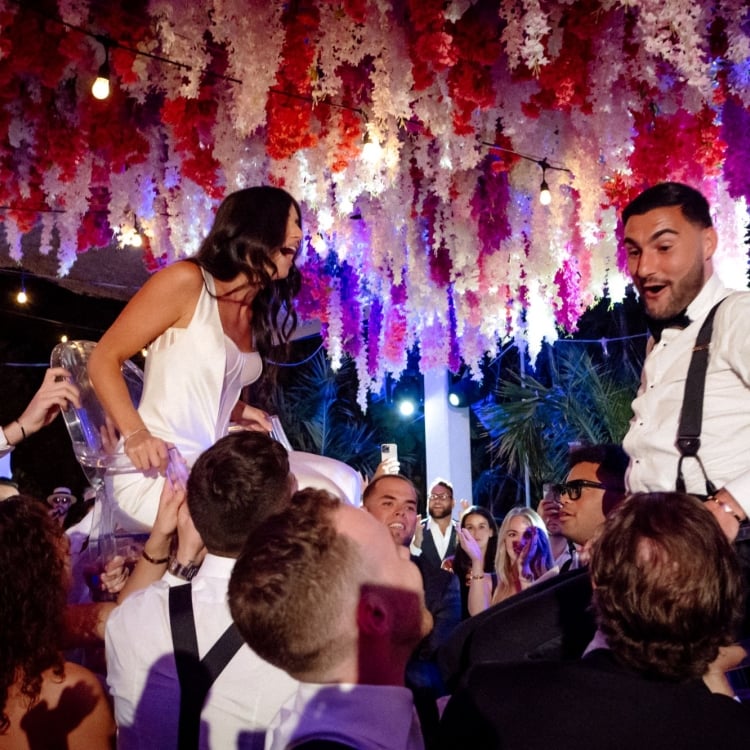 Bride and Groom being carried on their friends shoulders during wedding reception