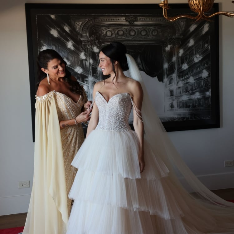 Angie and her mom smiling at each other in their wedding outfits