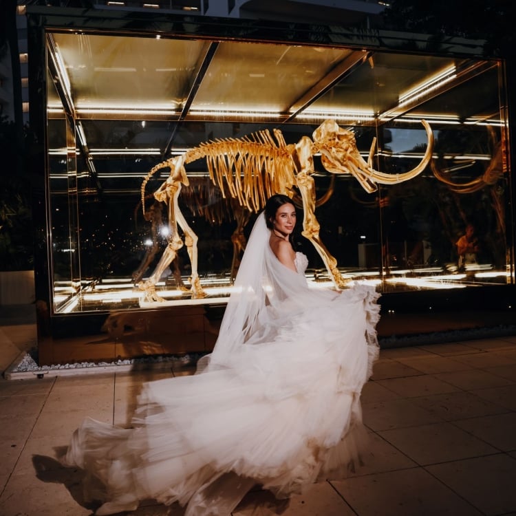 Angie standing in front of the gold mammoth skeleton at night