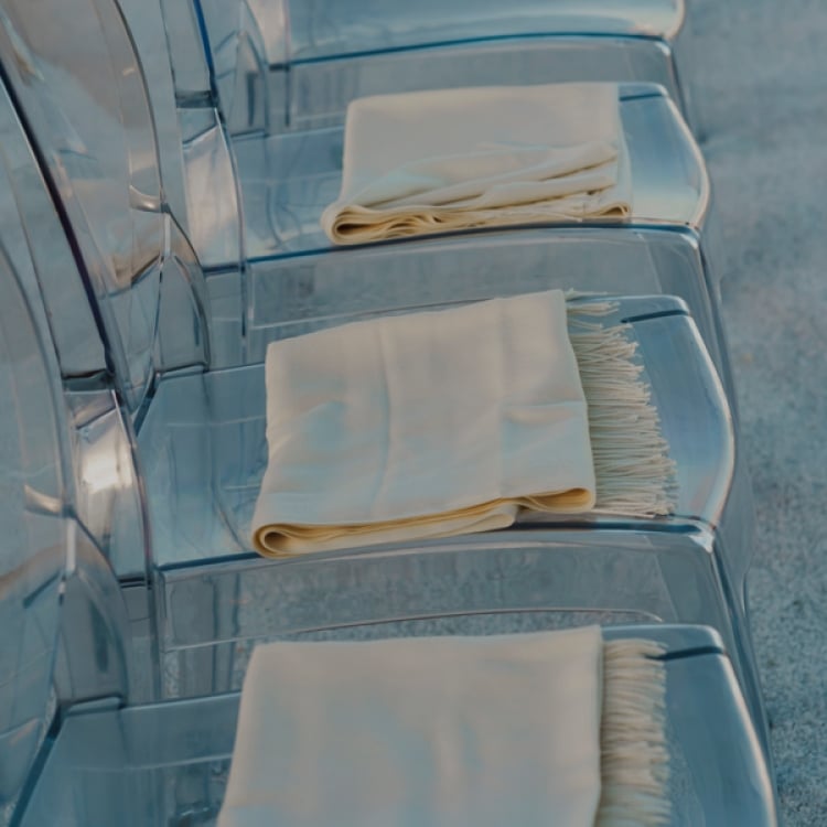 Clear chairs with scarves laid upon them