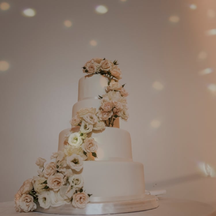 Simple wedding cake with white roses climbing up to the top