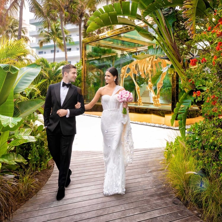 Bride & groom walking away from a mammoth skeleton encased in class