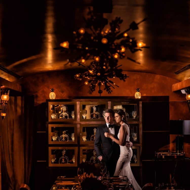 bride and groom stand in dimly lit room with a golden hue
