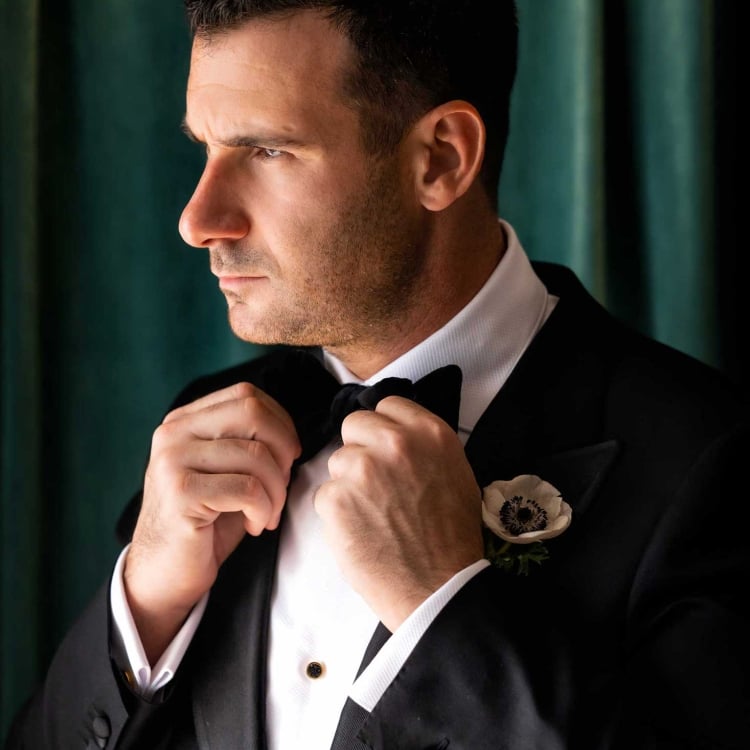 Groom fixing his tie.