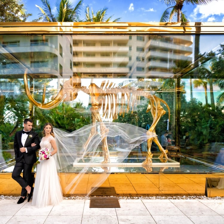 bride and groom stand in front of mammoth statue