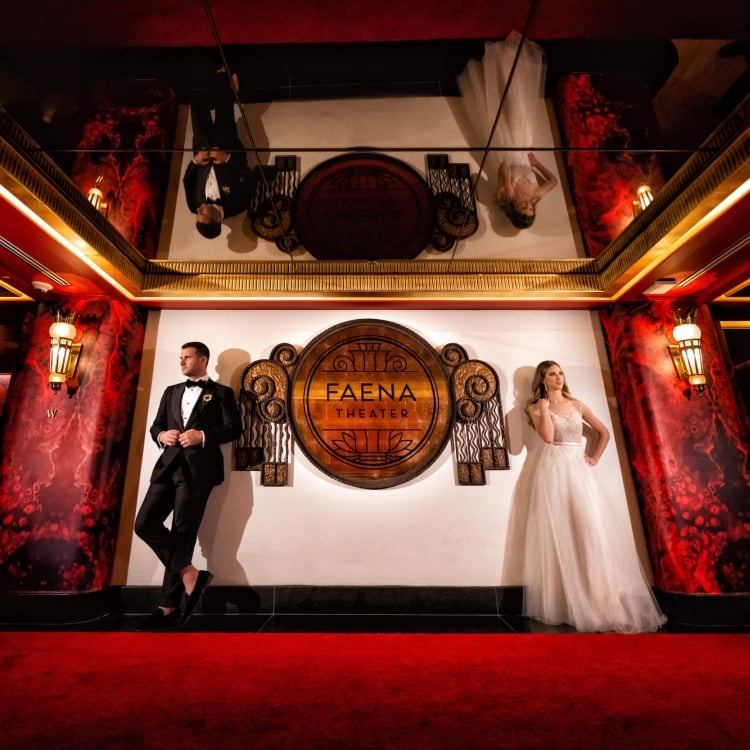 bride and groom stand on either side of Faena Theater sign