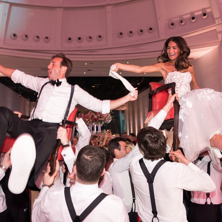 Allison and Robert Zale being carried in red chairs by the groomsmen