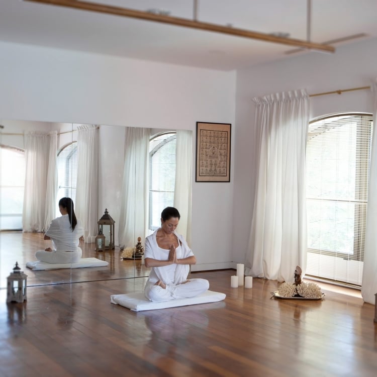 women sit on wood floor in yoga positions