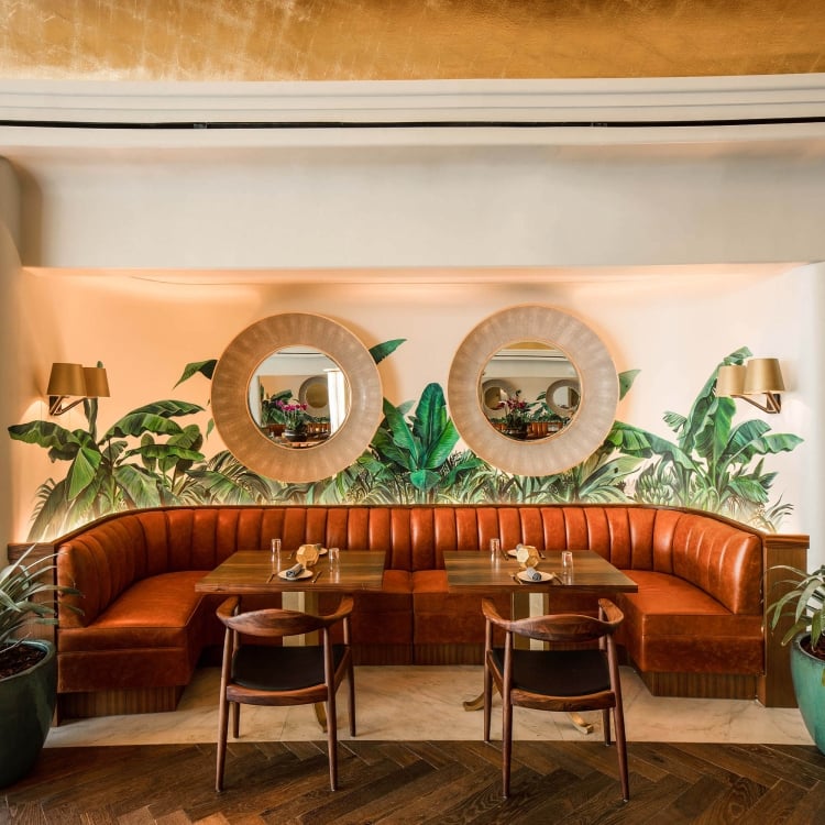 banquette seating dining area with palm leave mural