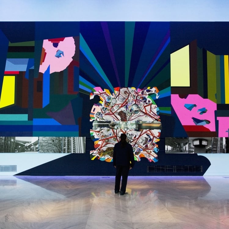 man stands in front of vibrant wall mural