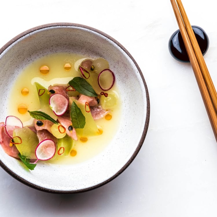 beautiful bowl of fish and broth with chopsticks beside