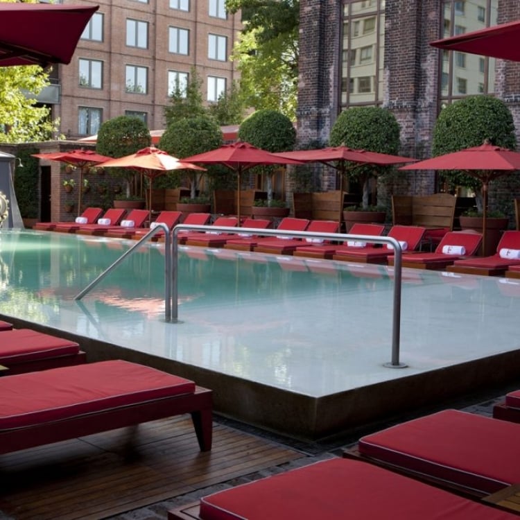 pool surrounded by red lounge chairs