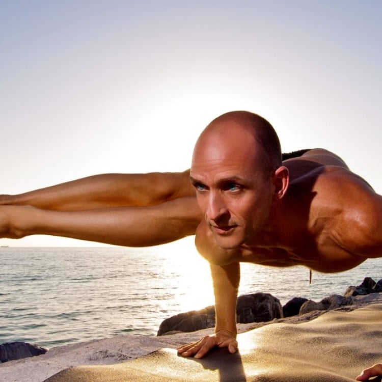 Tim Feldmann in yoga pose beside the ocean
