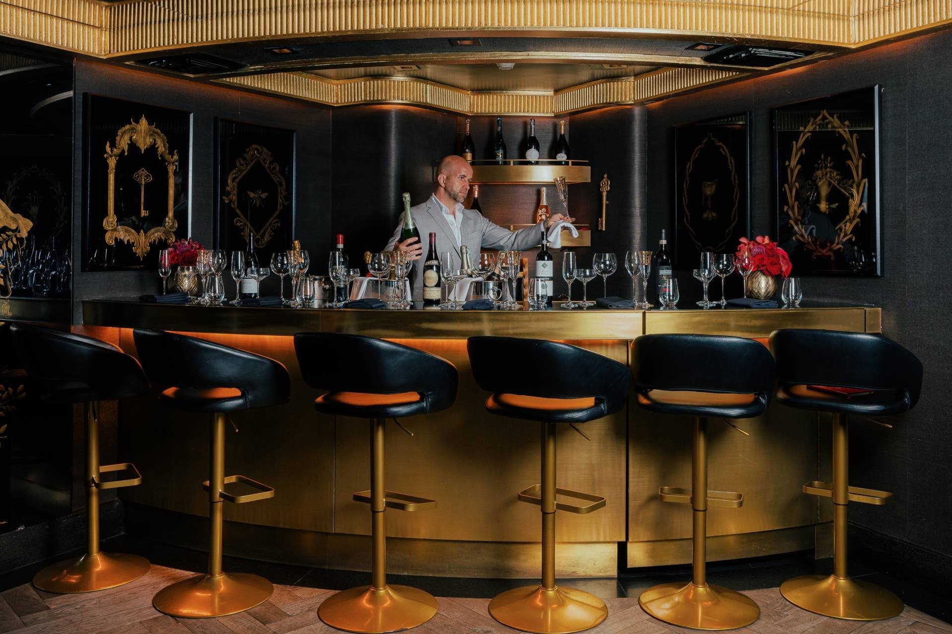 Sommelier standing behind the bar with a bottle of wine and a wine glass
