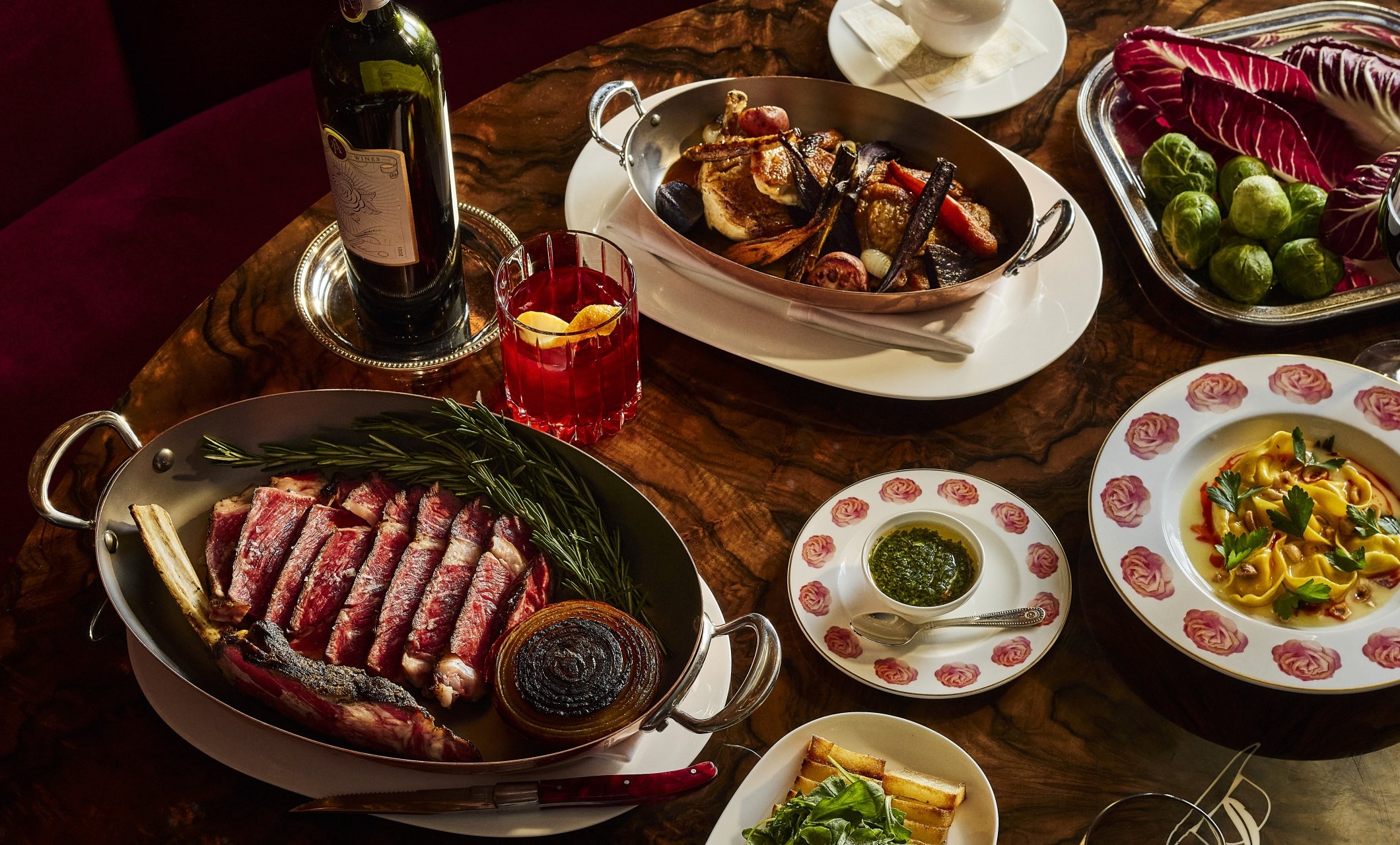 Thanksgiving dishes plated on rose plates with meat and wine