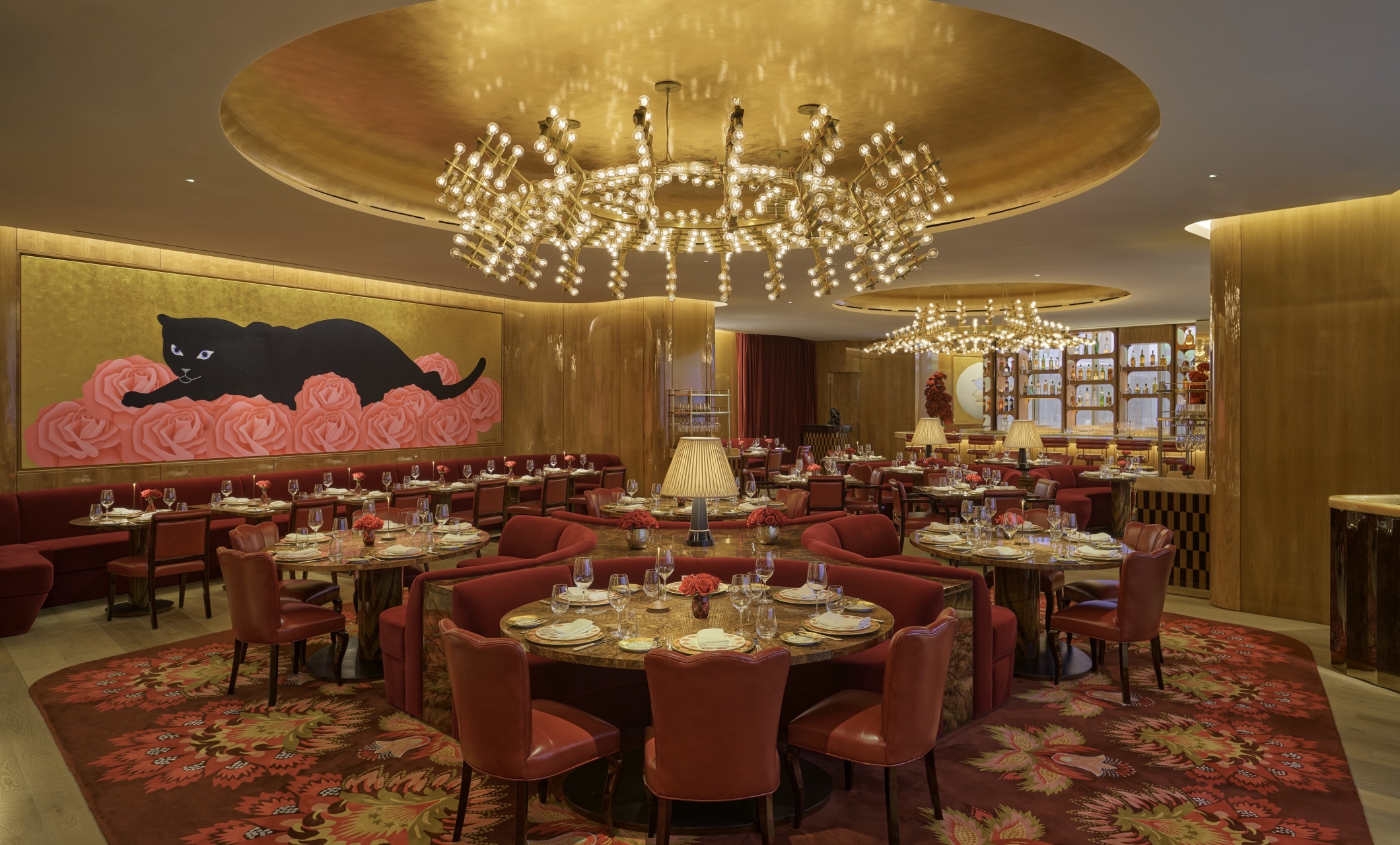 The dining room at La Boca, with gold walls and a mural featuring a black cat