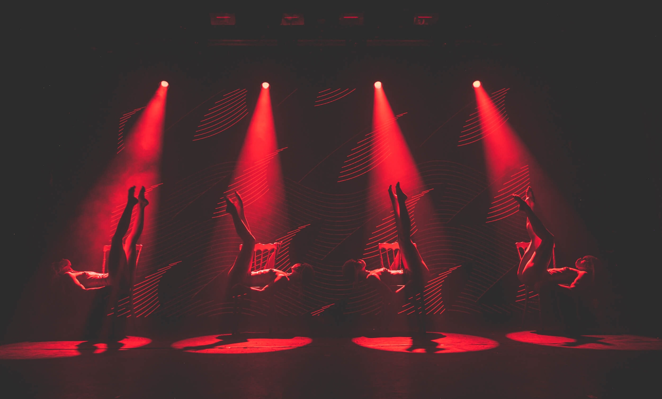 four Tryst Caberet dancers bathed in red spotlights
