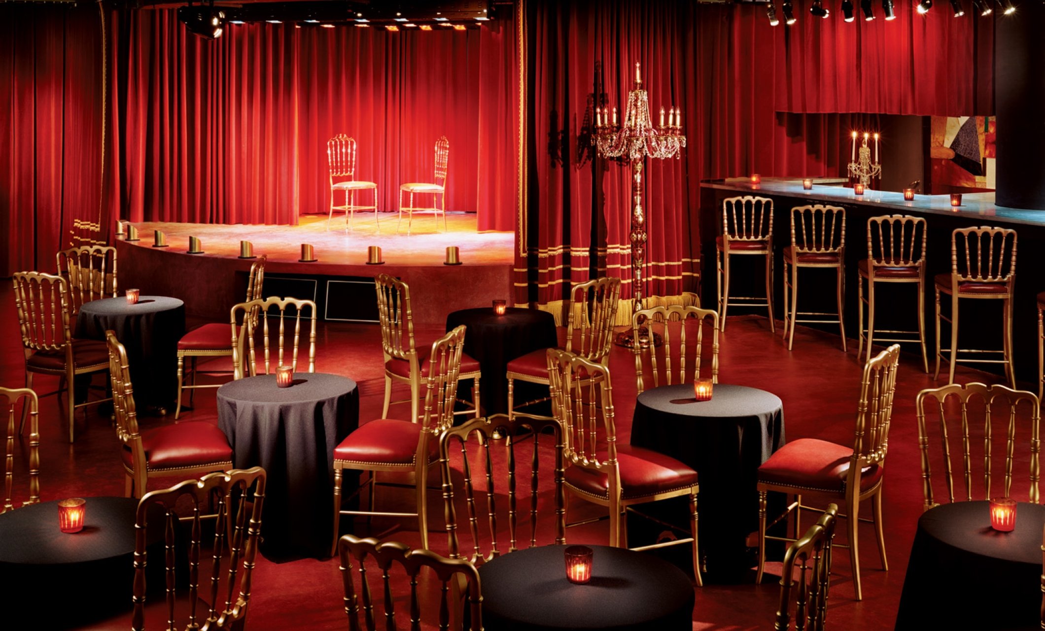 empty lounge area with chairs at multiple tables and a bar along with chairs on stage