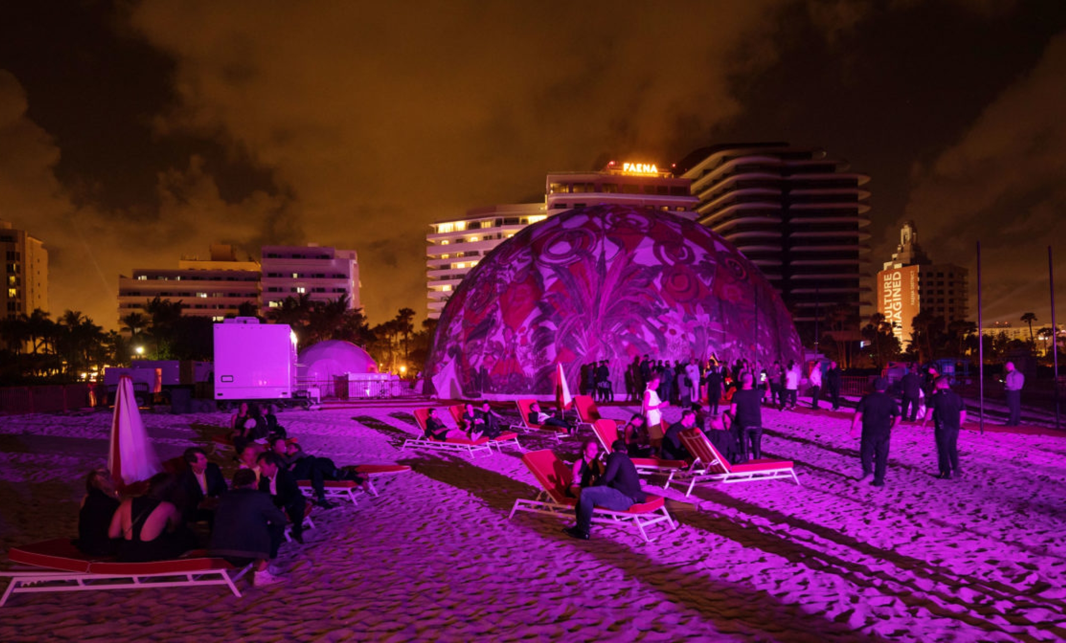 Lit up dome on beach with people socializing